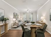 Thumbnail 5 of 38 - A dining room with a table set for two and a couch in the background.