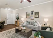 Thumbnail 6 of 38 - A living room with a grey couch, a coffee table, and a ceiling fan.