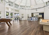 Thumbnail 19 of 38 - A billiard table is in the middle of a room with a white ceiling and wooden floors.
