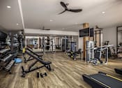 Thumbnail 6 of 16 - A spacious gym with a variety of equipment including a treadmill, weights, and a bench press.