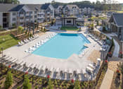 Thumbnail 42 of 49 - an aerial view of a resort style pool with chaise lounge chairs and a clubhouse in the