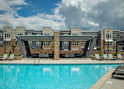 Thumbnail 27 of 31 - A swimming pool in front of a building with a sunny sky.