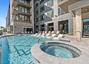 Thumbnail 15 of 34 - A large outdoor swimming pool with a hot tub in the middle of it.