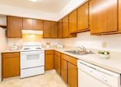 Thumbnail 15 of 26 - A kitchen with wooden cabinets and white appliances at Winchell Way Apartment , Kalamazoo, 49008