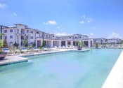 Thumbnail 1 of 60 - a large pool with lounge chairs and buildings in the background
