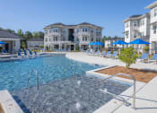 Thumbnail 16 of 54 - a large pool with blue umbrellas in front of an apartment building