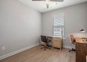 Thumbnail 15 of 65 - A room with a desk, chair, and a window with blinds.