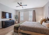 Thumbnail 19 of 65 - A bedroom with a bed, dresser, and ceiling fan.