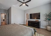 Thumbnail 20 of 65 - A bedroom with a bed, dresser, and ceiling fan.