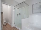 Thumbnail 22 of 65 - A white bathroom with a glass shower door and a white bathtub.