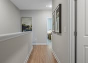 Thumbnail 14 of 65 - A hallway with a painting on the wall and a door on the right.