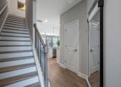 Thumbnail 28 of 65 - A staircase with a wooden handrail and steps leads to a brightly lit room with white doors.