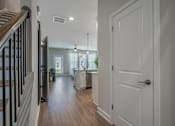 Thumbnail 29 of 65 - A hallway with a white door and a staircase with black railings.