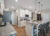 Thumbnail 31 of 65 - A kitchen with a marble countertop and white cabinets.