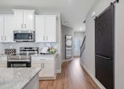 Thumbnail 35 of 65 - A kitchen with white cabinets and a black refrigerator.