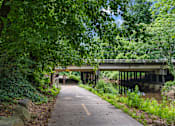 Thumbnail 35 of 38 - A pathway with a bridge in the background.
