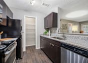 Thumbnail 6 of 38 - A kitchen with dark brown cabinets and a stainless steel dishwasher.