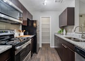 Thumbnail 2 of 38 - A kitchen with dark wood cabinets and a black stove top oven.