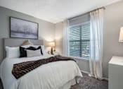 Thumbnail 8 of 38 - A bedroom with a large bed and a window with white curtains.