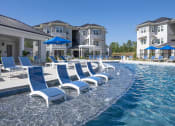 Thumbnail 15 of 54 - a row of blue lounge chairs in a pool with a building in the background