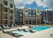 Thumbnail 25 of 31 - A large swimming pool in front of apartment buildings.