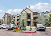 Thumbnail 36 of 42 - A parking lot with cars and a building in the background.