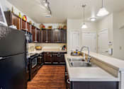 Thumbnail 4 of 42 - A kitchen with a black refrigerator and wooden cabinets.