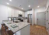 Thumbnail 18 of 28 - Huntsville, AL Luxury Apartments - The Kelvin - Kitchen with Luxury Vinyl Tile Flooring, Breakfast Bar with Seating, Granite Countertops, White Shaker-Style Cabinets, and Stainless-Steel Appliances.