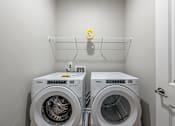 Thumbnail 50 of 65 - two washing machines in a laundry room with a shelf above them
