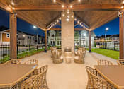 Thumbnail 61 of 71 - a covered patio with tables and chairs at night