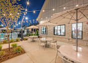Thumbnail 58 of 71 - a patio with tables and umbrellas and a pool at night