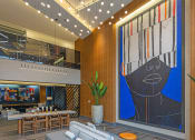 Thumbnail 22 of 47 - a lobby with a blue rug and a couch and a large painting