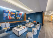 Thumbnail 27 of 47 - a living room with a blue wall and blue couches and tables