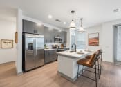 Thumbnail 2 of 21 - a kitchen with stainless steel appliances and a white island with stools