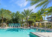 Thumbnail 19 of 38 - a swimming pool with palm trees and umbrellas around it
