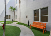 Thumbnail 34 of 38 - an orange bench in front of a white building with palm trees