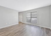 Thumbnail 22 of 35 - an empty living room with a large window and wood flooring