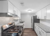 Thumbnail 21 of 35 - a kitchen with white cabinets and a stove and refrigerator