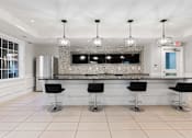 Thumbnail 4 of 39 - A modern kitchen with a bar area and black stools.