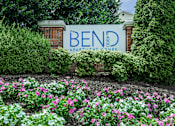 Thumbnail 1 of 37 - A sign for Bend Apartment Homes is surrounded by flowers.