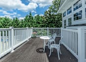 Thumbnail 12 of 37 - A white table and chairs are on a wooden deck.