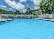 Thumbnail 2 of 37 - A large swimming pool with blue water and white lounge chairs.