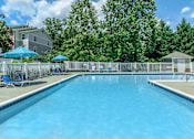 Thumbnail 3 of 37 - A large swimming pool surrounded by a fence and trees.