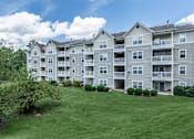 Thumbnail 32 of 37 - A large apartment complex with a green lawn in front.