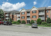 Thumbnail 36 of 37 - A large brick apartment building with a parking lot in front.