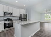 Thumbnail 26 of 49 - A kitchen with white cabinets and a large island.