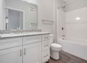 Thumbnail 27 of 49 - A white bathroom with a marble countertop and a white toilet.