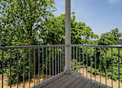 Thumbnail 29 of 49 - A deck with a metal railing and a tree in the background.