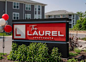 Thumbnail 49 of 49 - A sign for The Laurel Apartments is displayed in front of a building.
