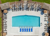 Thumbnail 25 of 32 - Apartments for Rent in Mt Juliet, TN - The Enclave at Providence - Aerial View of Resort-Style Pool with Sundeck, Submerged and Poolside Lounge Seats, Gazebos, and Umbrella Tables with Chairs.